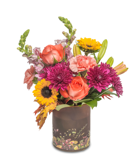 Festive fall vase with autumn leaves at the base, filled with sunflowers, carnations, roses, fall mums, and preserved oak leaves, capturing the vibrant colors of the season.