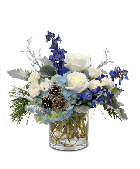 Frozen Blues' winter display with blue hydrangeas, white roses, and pinecones in a glass centerpiece—serene winter charm.