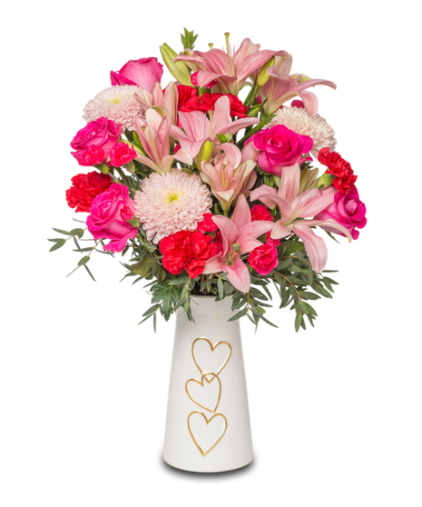 XOXO floral arrangement with red carnations, pink roses, lilies, and linette mums in pink and red hues. Designed as a sweet Valentine’s Day gift.