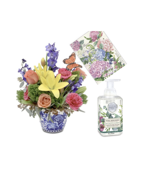 Floral arrangement of roses, lilies, and tulips in a blue and white ceramic vase, with foaming soap and a decorative tea towel, perfect for gifting.