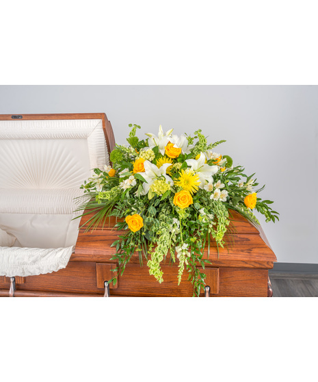 Serenity Casket Spray: A stunning floral arrangement in greens, whites, and yellows, a heartfelt tribute to a beloved soul