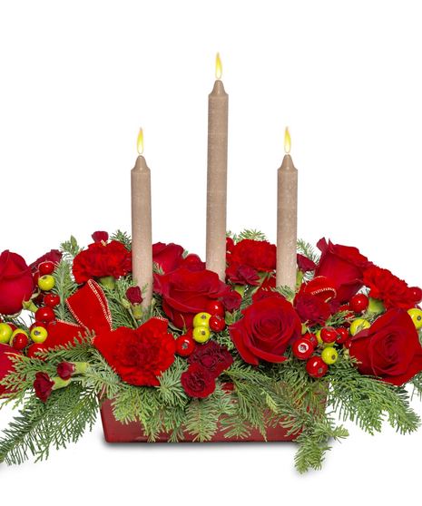 Christmas centerpiece with red roses, red carnations, red and green berries, and velvet ribbon tucks with a candle centerpiece