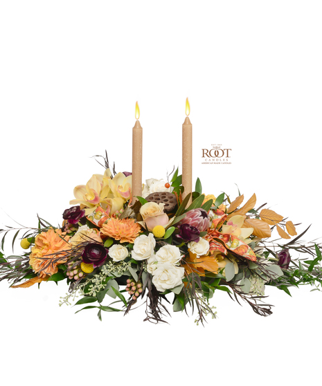  centerpiece with ivory roses, burgundy ranunculus, Mink Protea, orange dahlias, dried accents, and Root candles in a luxurious fall arrangement