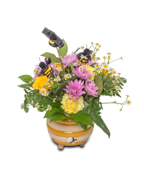 A honey pot vase holds a mix of yellow, green, and lavender flowers with small felt bees buzzing above, creating a cheerful and whimsical display.