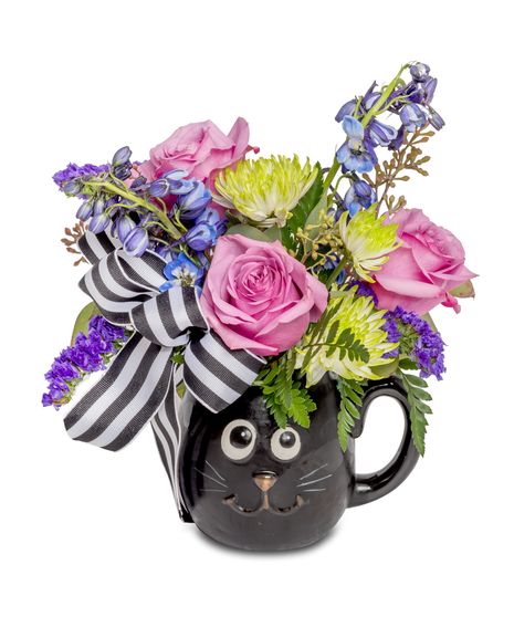 Whimsical Halloween floral arrangement with pink roses, blue delphinium, and green button mums in a black cat mug with a striped bow