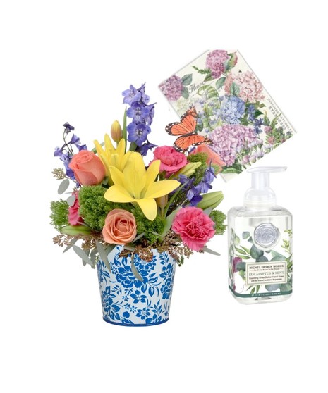 Floral arrangement of roses, lilies, and tulips in a blue and white ceramic vase, with foaming soap and a decorative tea towel, perfect for gifting.