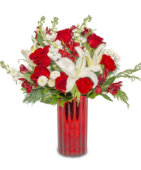 Winter's Haven floral arrangement in a red glass vase with white lilies, red roses, carnations, button mums, red alstroemeria, cedar, and pine wintergreens