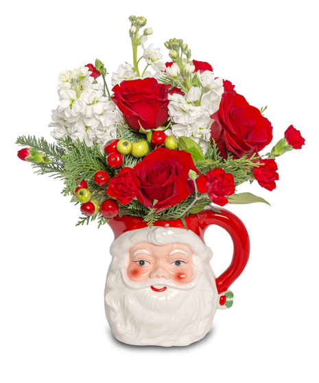 Santa Claus floral arrangement in a milk or cocoa pitcher with red roses, green and red berries, white blooms, miniature red carnations, and wintergreens