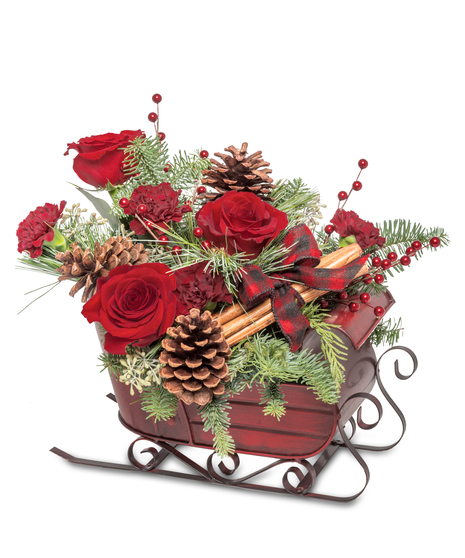 Holiday sleigh centerpiece with red roses, pinecones, cinnamon sticks, evergreen branches, and red berries