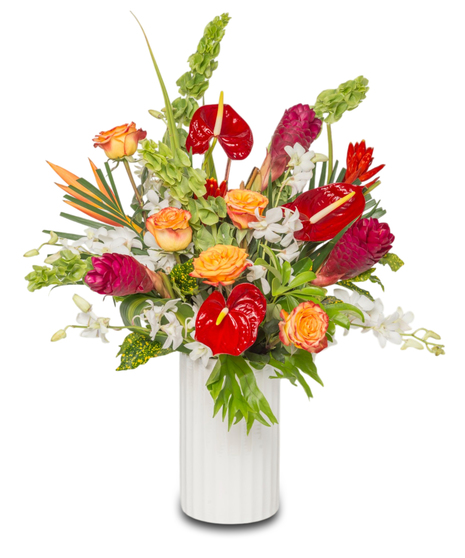 A vibrant tropical floral arrangement in a sleek white ceramic vase featuring red anthuriums, white orchids, gingers, and lush greenery.