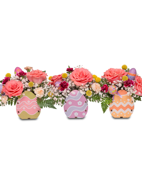 A petite wooden crate filled with bright florals including baby's breath, miniature carnations, and peach roses, adding a touch of springtime charm.