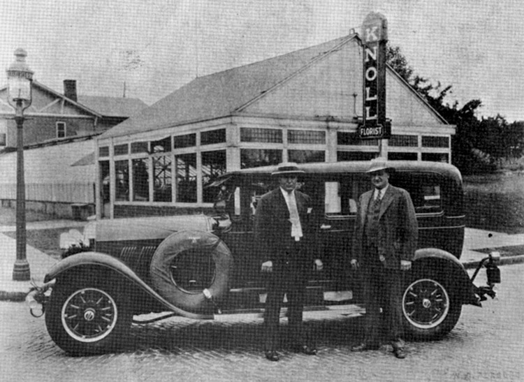 John and Herman Knoll, standing alongside a very early automobile, in the late 19th century